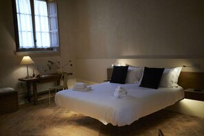 A hotel room with a large bed, a desk with a lamp, a chair, and a window with curtains. - Badia Giulia - Adults Only (Camaiore)