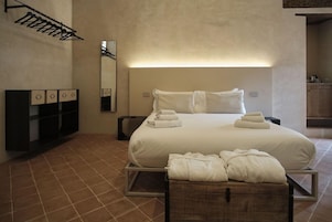 Habitación de hotel con una cama grande, una mesita de noche, un espejo y un armario.