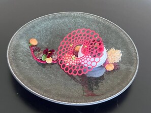 A round plate with a central pink decorative element, surrounded by various food items and garnishes. - Secluded Chalet Retreat near Kruger Park, Luxury Meets Nature, Farm living (Kiepersol)
