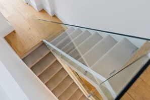 A modern interior with a glass railing, wooden flooring, and a patterned wall. - Luxury 3BDR Chelsea Townhouse Sleeps 6 (London)