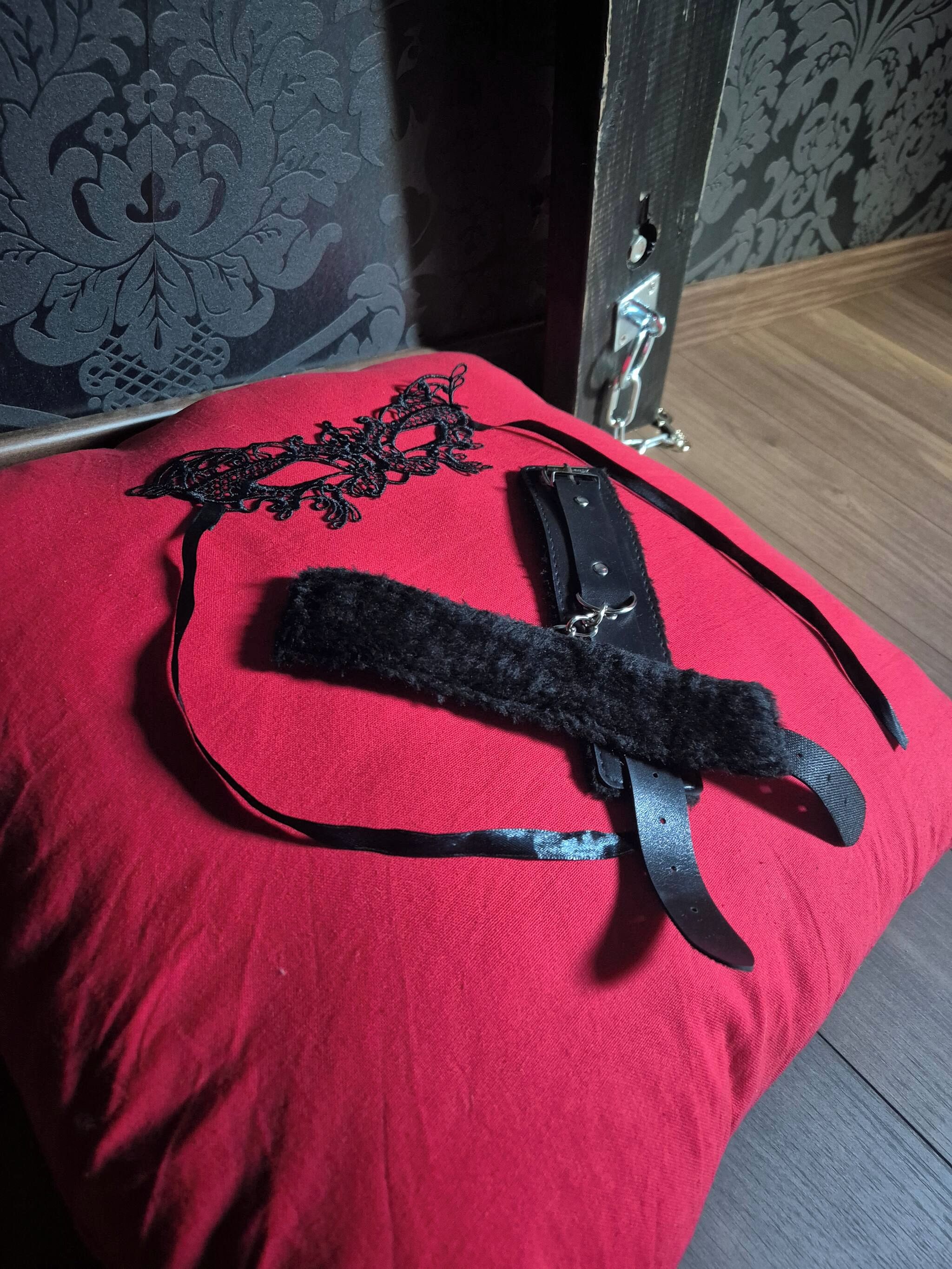 Un coussin rouge orné de dentelle noire et muni d’une bande noire.