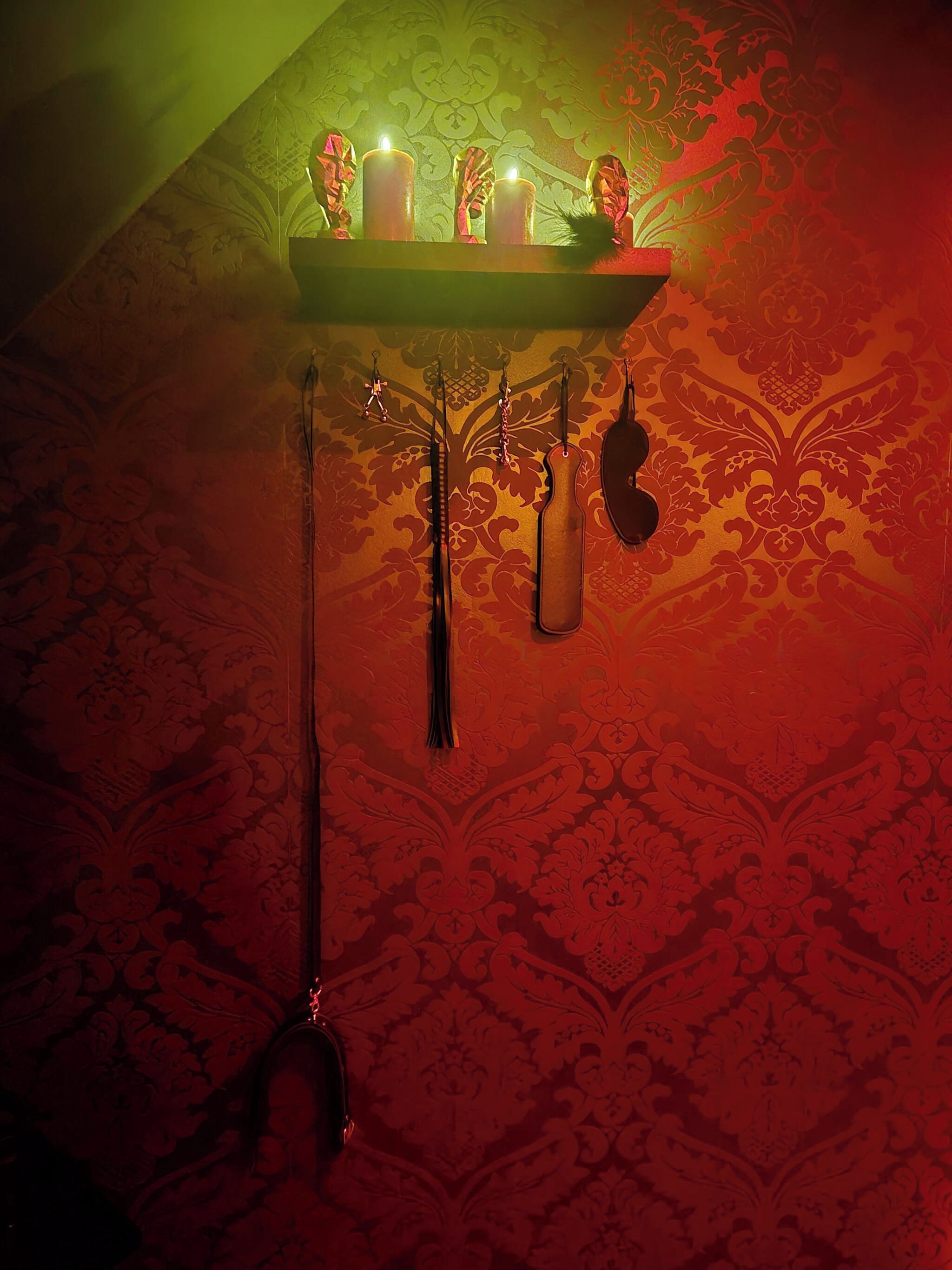 Una mesa con velas y objetos colgantes frente a una pared con diseño.
