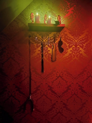 A table with candles and hanging items against a patterned wall.