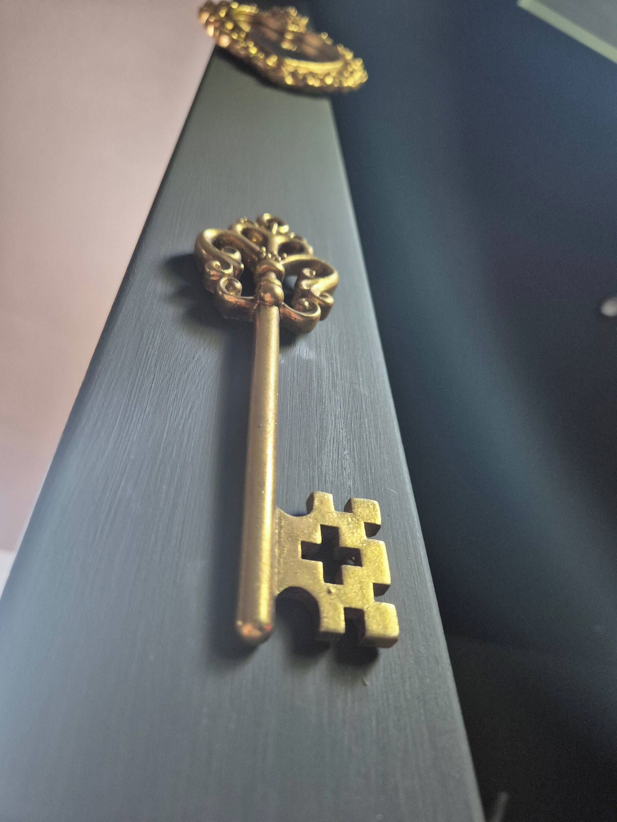 A golden key with intricate designs on a dark surface.
