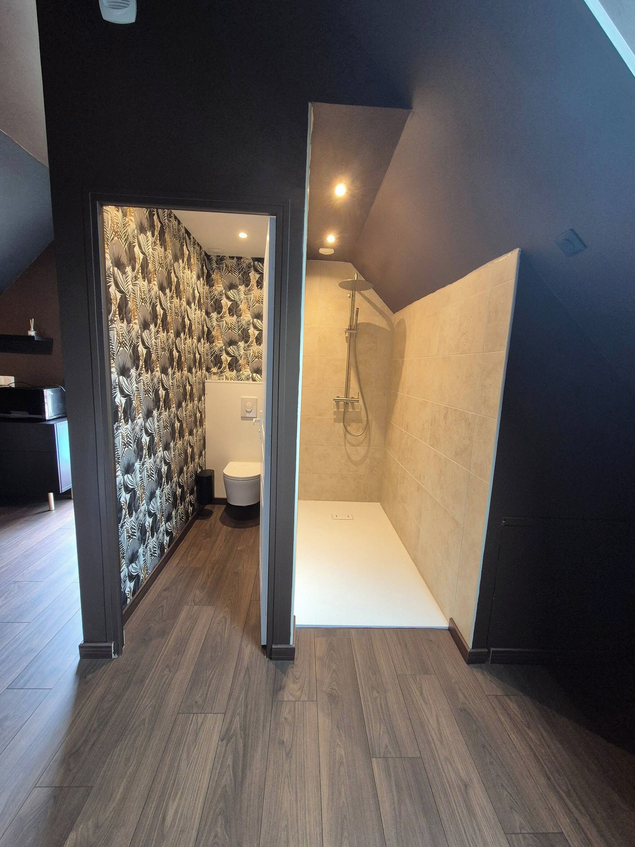 A modern bathroom with a shower, a toilet, and a patterned wall.