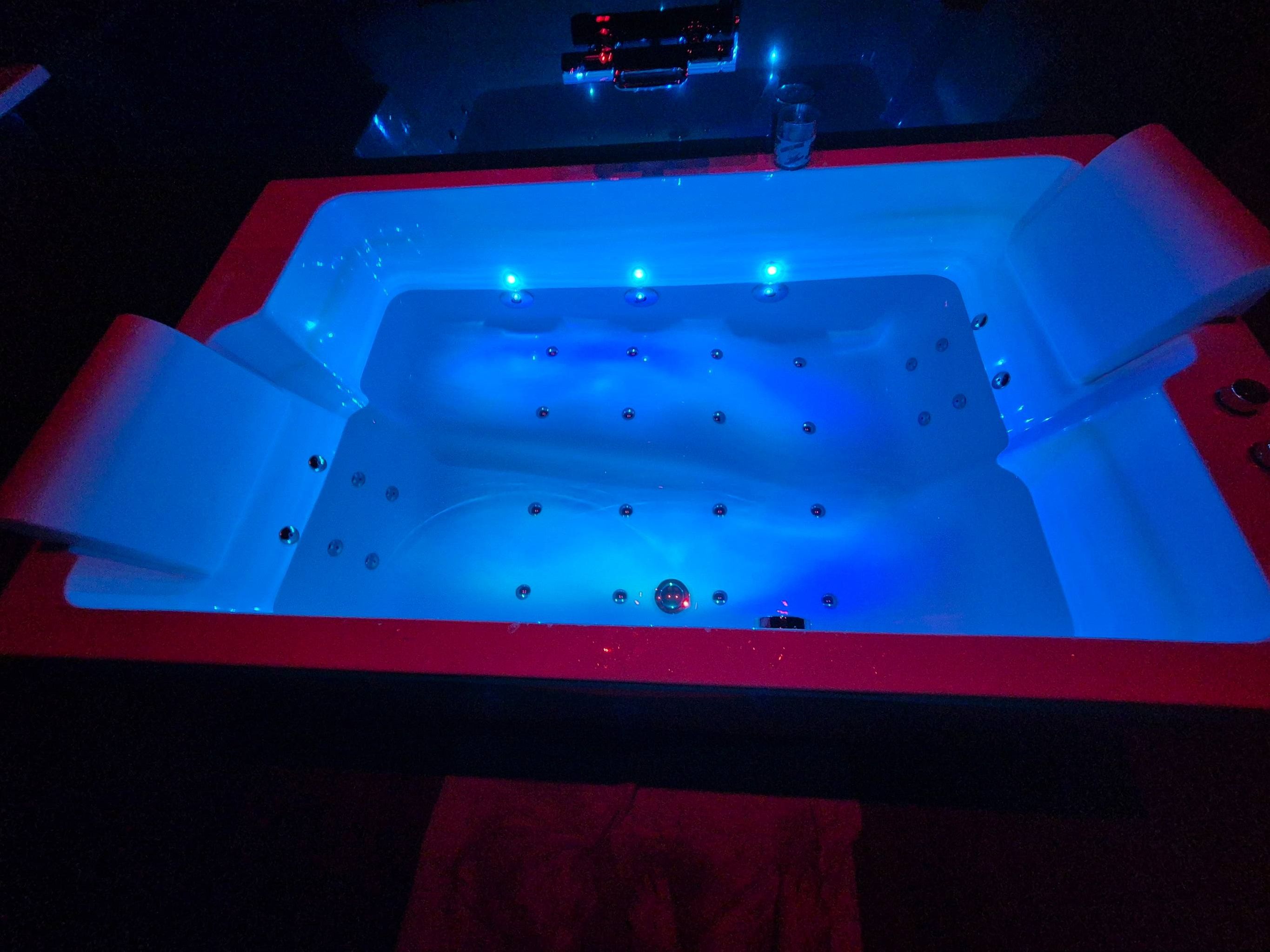 Un bain à remous doté de plusieurs jets, un verre et une serviette rouge.