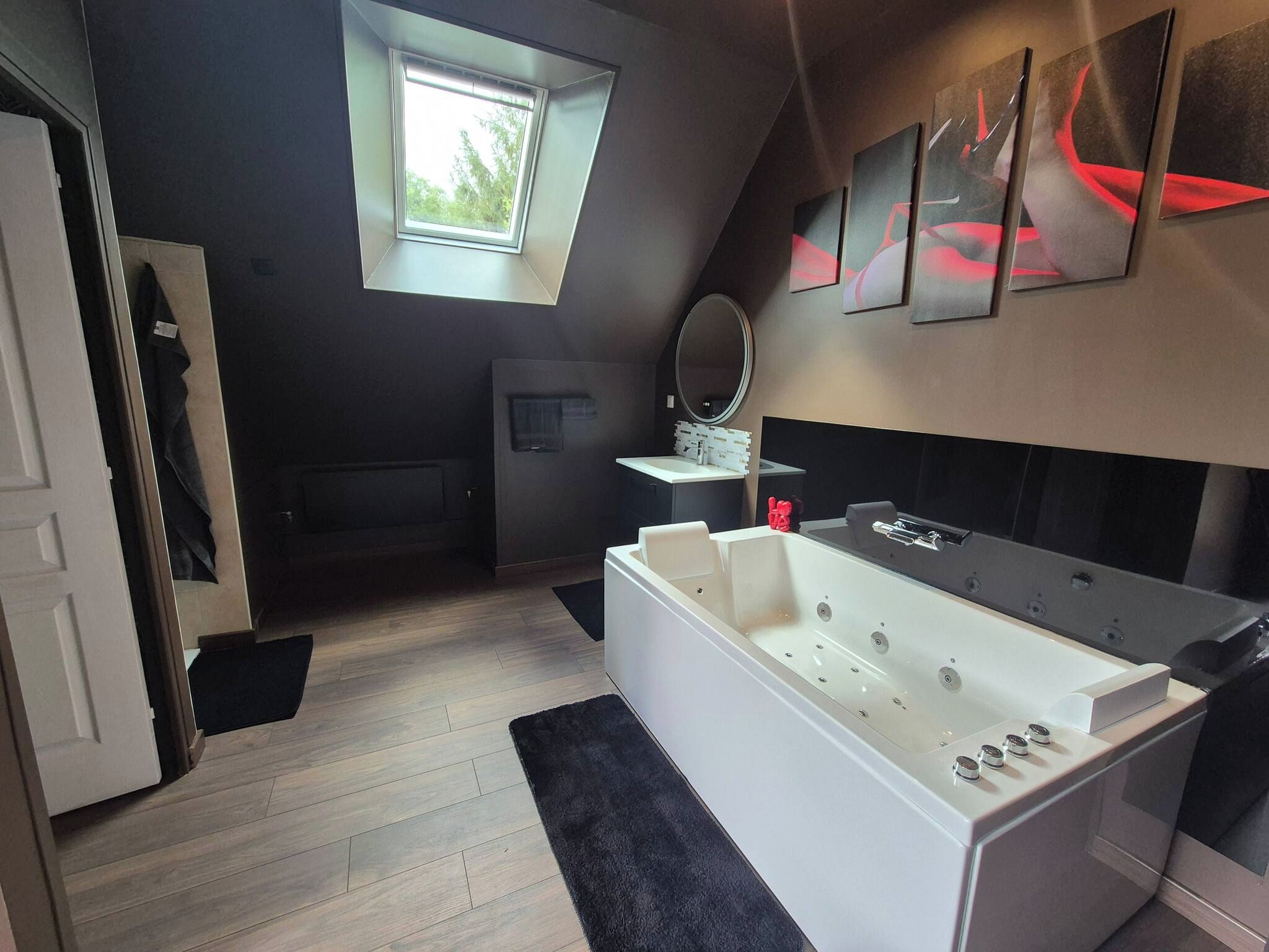 A modern bathroom with a large bathtub, a window, and abstract wall art.