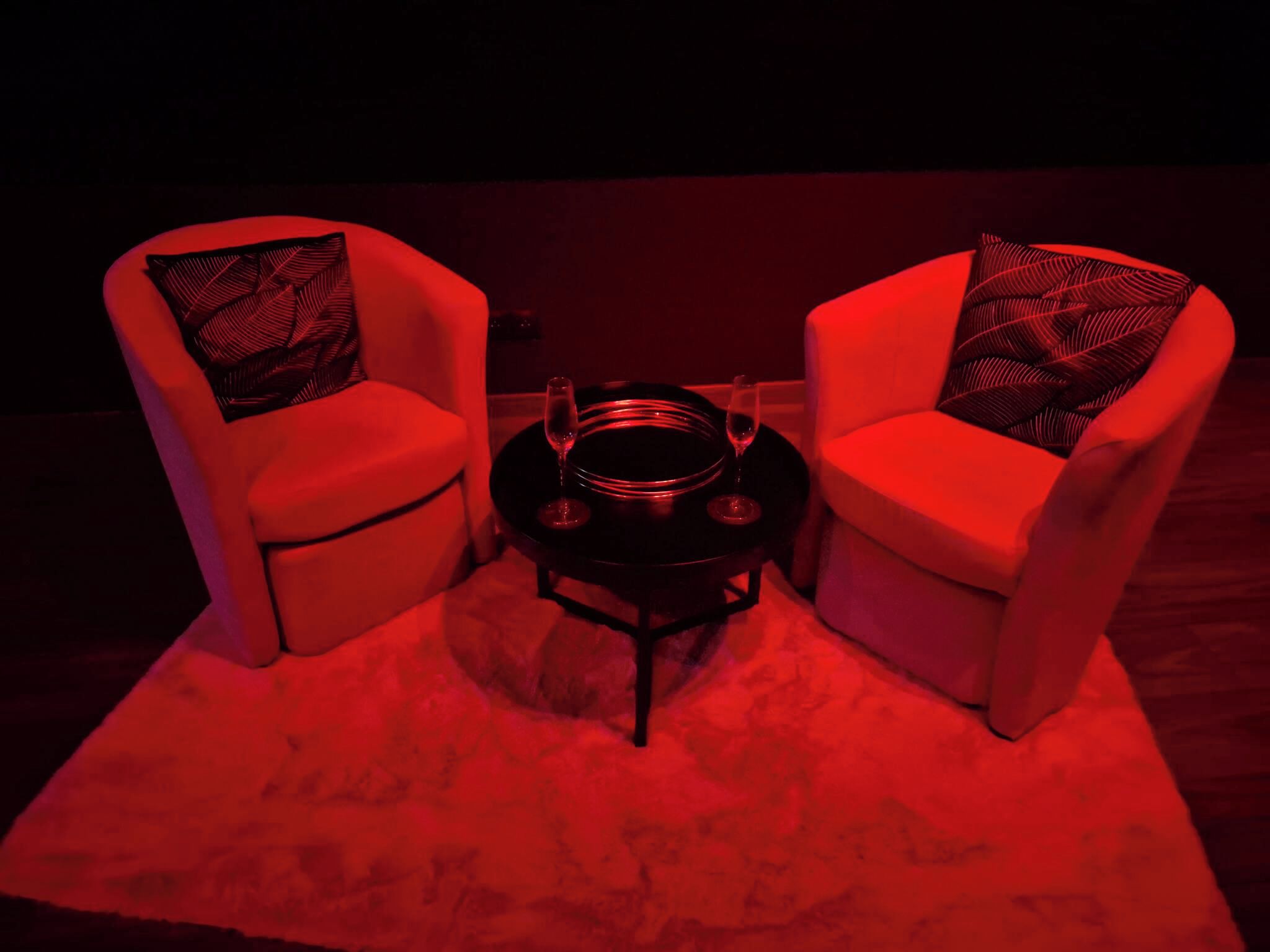 Two armchairs with patterned cushions, a small round table with a metal base, and a red carpet.