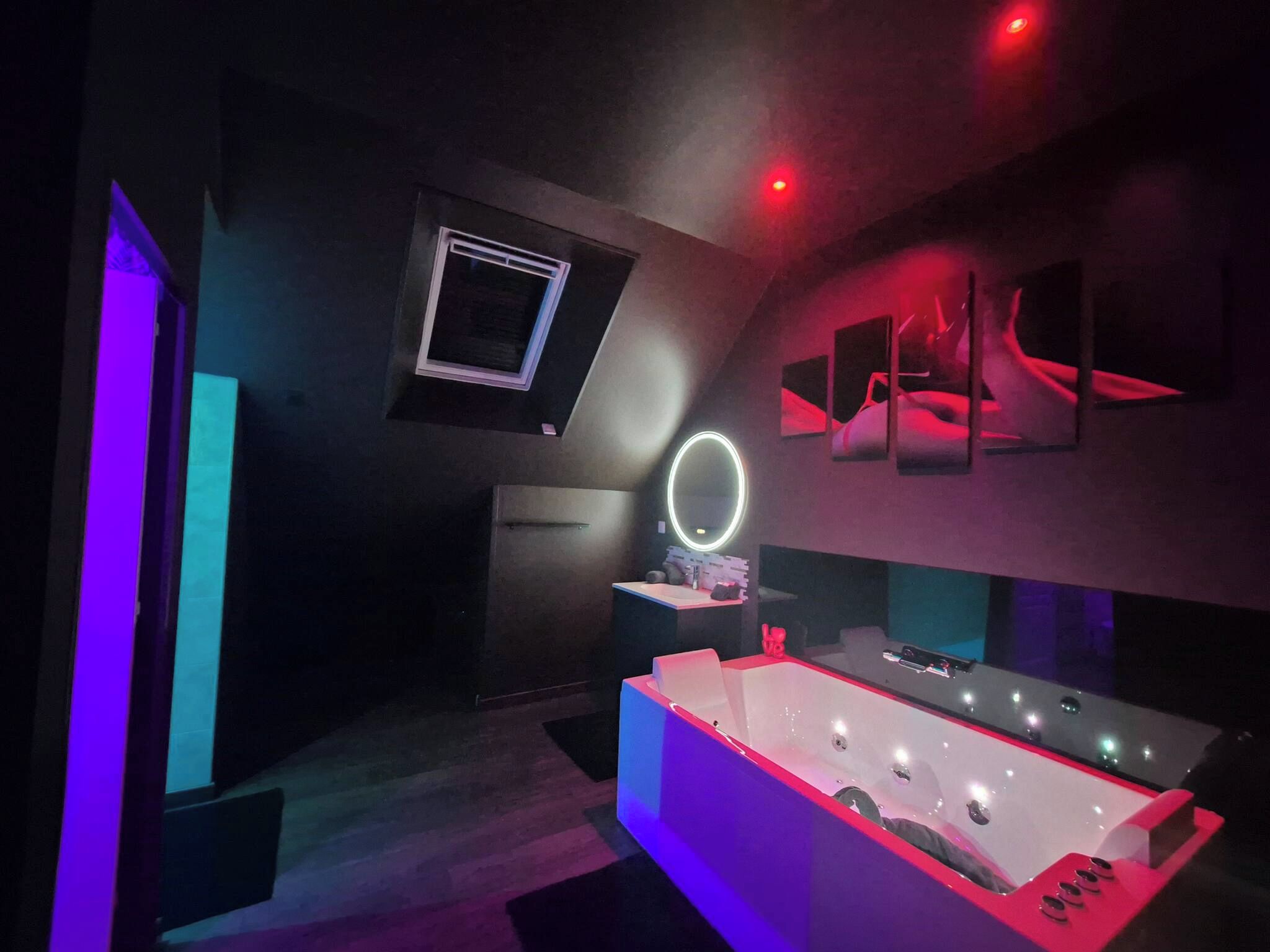 A modern bathroom with a large bathtub, a vanity with a mirror, and a wall-mounted sink.