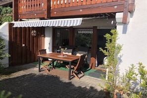 A patio with a wooden table and chairs, a covered seating area, and a wooden fence. - Holiday apartment in Forbach with Wi-Fi (Forbach)
