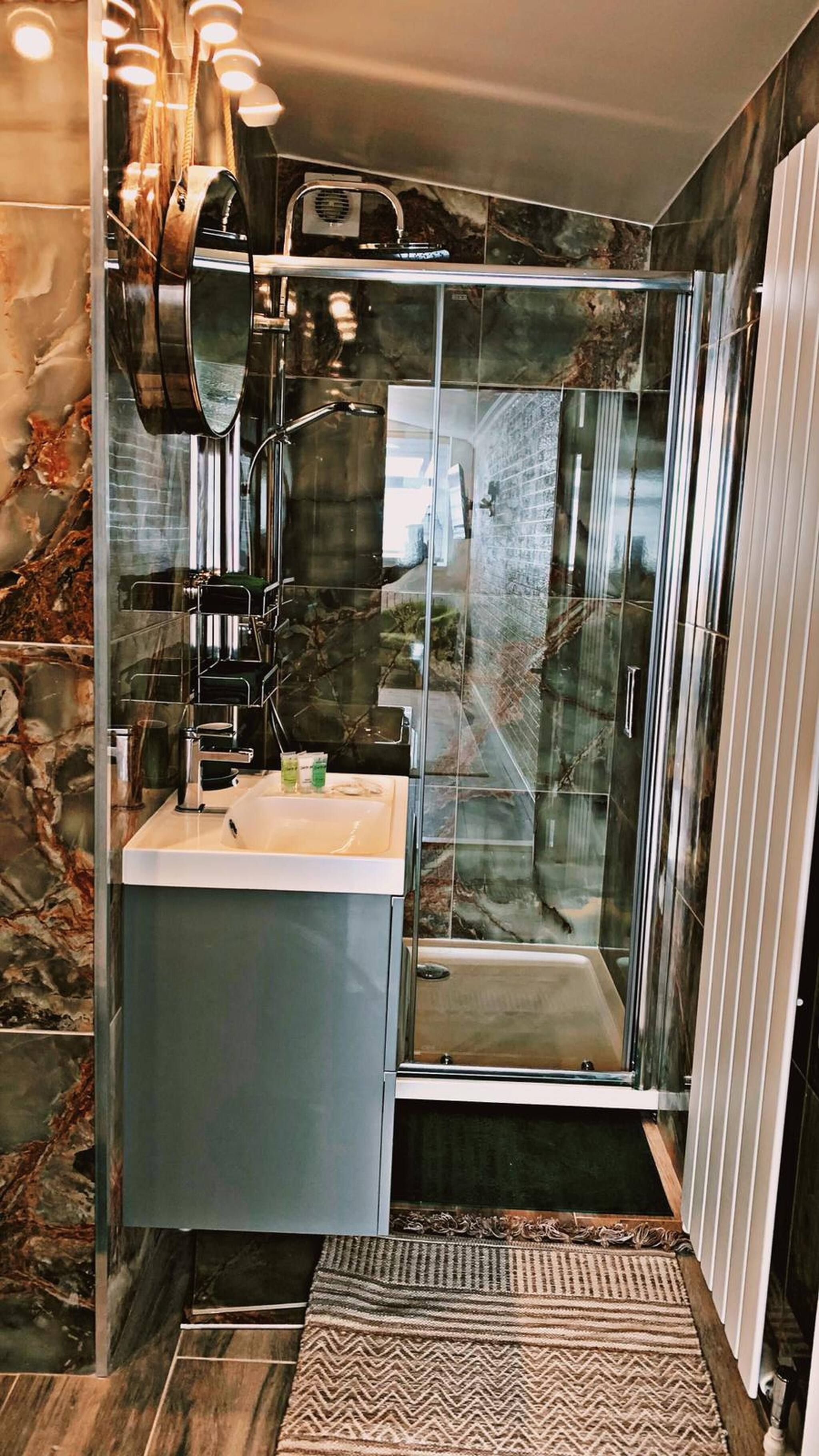Une salle de bain moderne avec une douche à parois de verre, un meuble-lavabo avec miroir et un pare-baignoire en marbre.