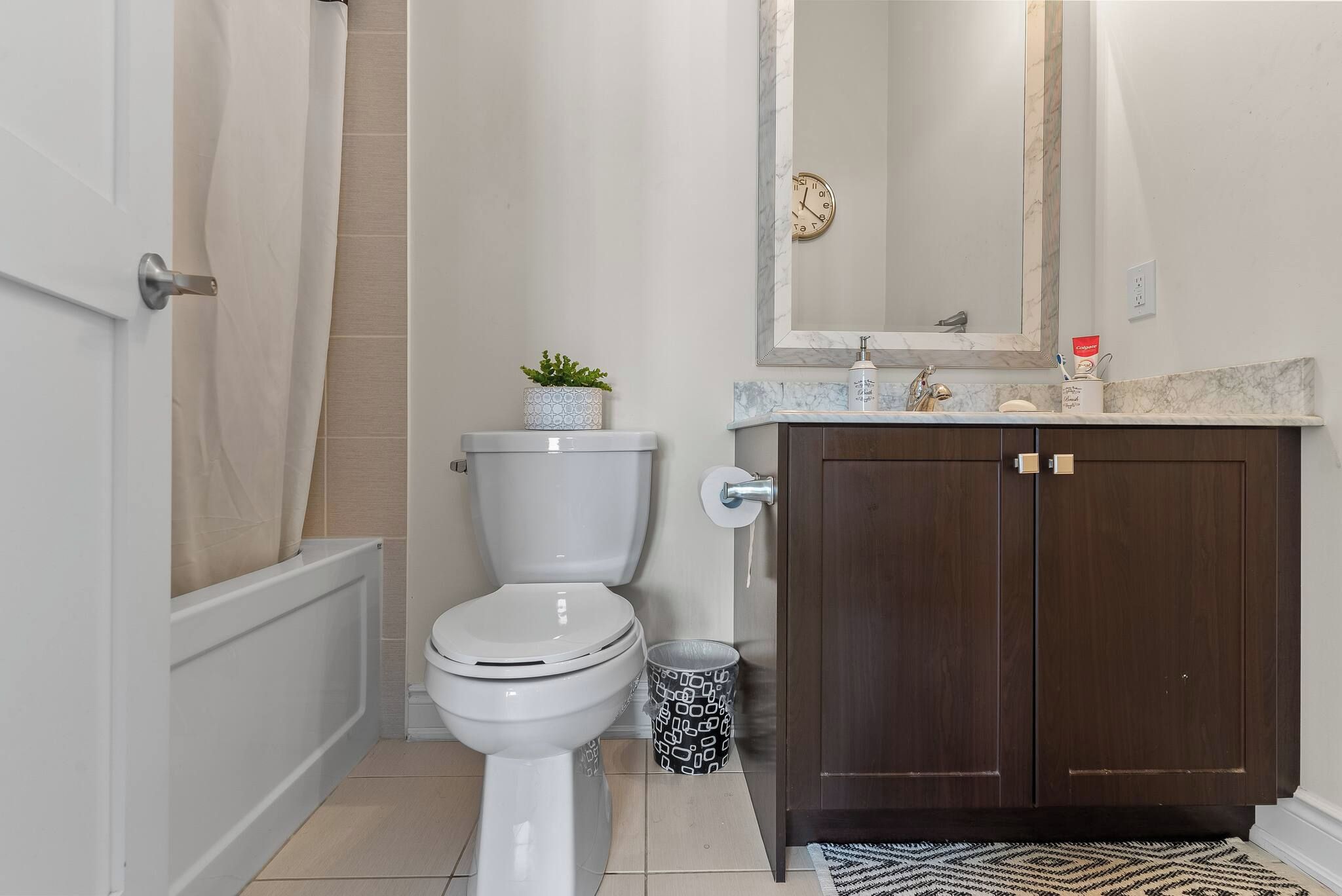 A bathroom with a toilet, a sink, a mirror, and a shower curtain.