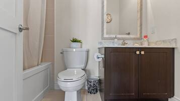 A bathroom with a toilet, a sink, a mirror, and a shower curtain.