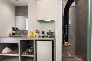 Ein modernes Badezimmer mit Duschkabine, Waschbecken und einem kleinen Kühlschrank.