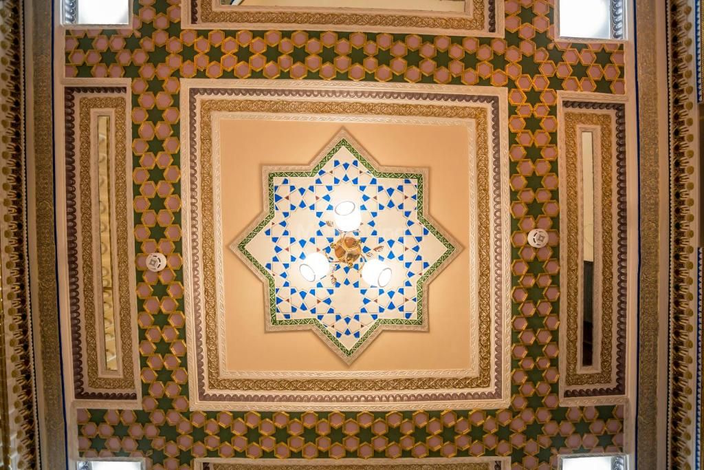 A detailed geometric ceiling design with a central star-like pattern surrounded by smaller shapes.