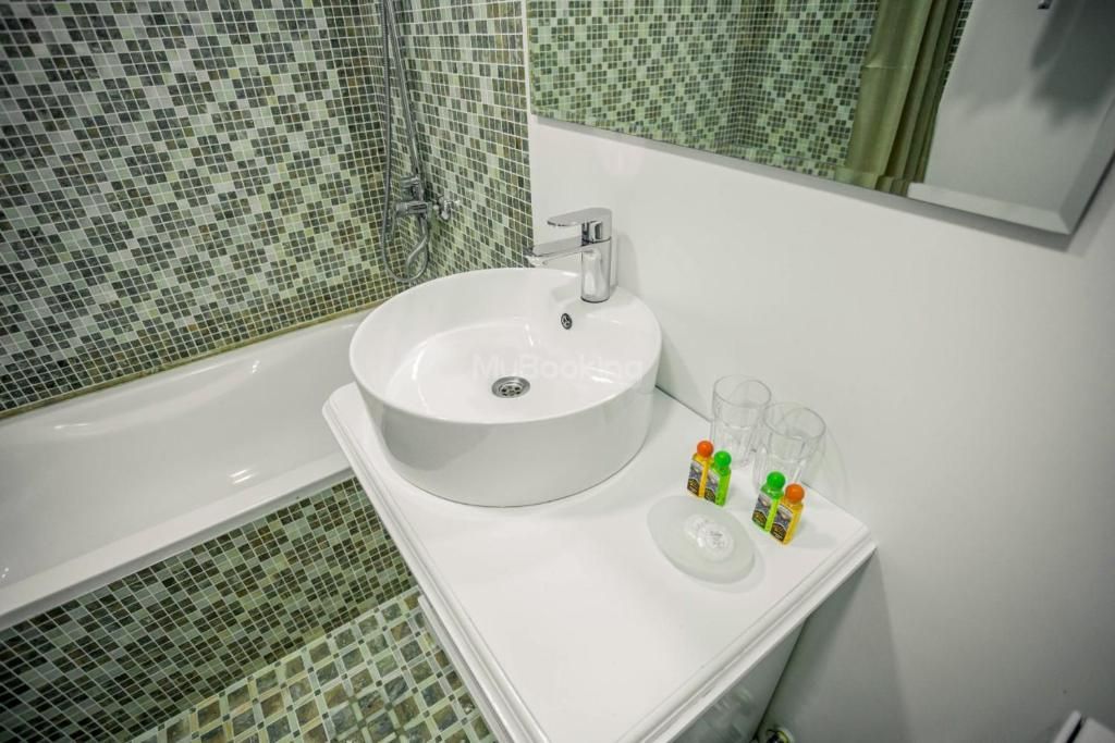 A bathroom with a white sink, a shower, and a mirror.