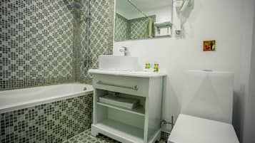 A bathroom with a bathtub, a sink, a mirror, and a hairdryer.