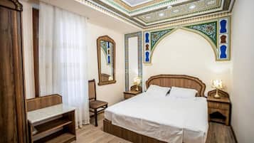 A hotel room with a wooden bed, a desk, a chair, and a large mirror.