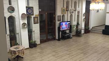 A spacious room with a wooden floor, a television, and a staircase leading to an upper level.