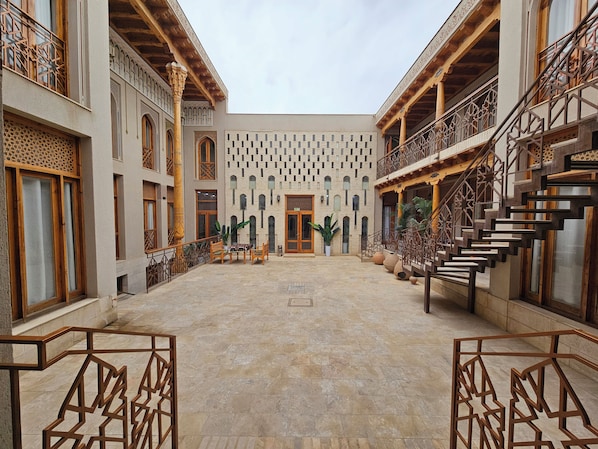 Un patio con un espacio abierto central, rodeado de edificios con elementos arquitectónicos tradicionales.