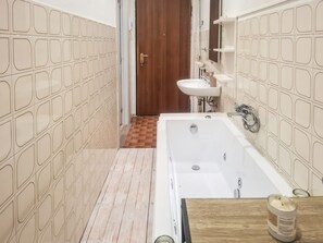 Un baño con bañera, lavamanos y tocador de madera.