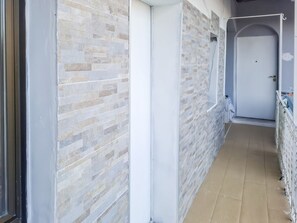 Un pasillo con pared de azulejos, una puerta cerrada y un enchufe visible.