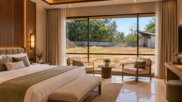 A modern bedroom with a large bed, two armchairs, a small round table, and a view of the outdoors.