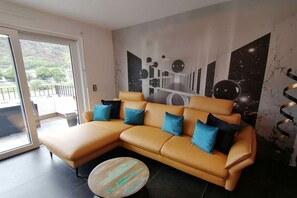 A modern living room with a sectional sofa, a round coffee table, and a mural of celestial bodies on the wall. - FeWo Excellence Juwel (Cochem)