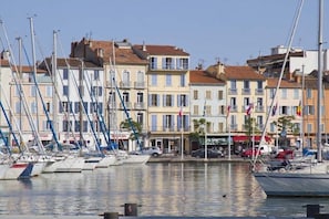 A marina with boats docked, buildings with balconies, and flags. - Holiday apartment with 2 bedrooms (La Seyne sur Mer)