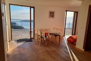 A dining area with a table and chairs, a view of the sea through open doors, and a framed picture on the wall. - Holiday apartment with 2 bedrooms (La Seyne sur Mer)