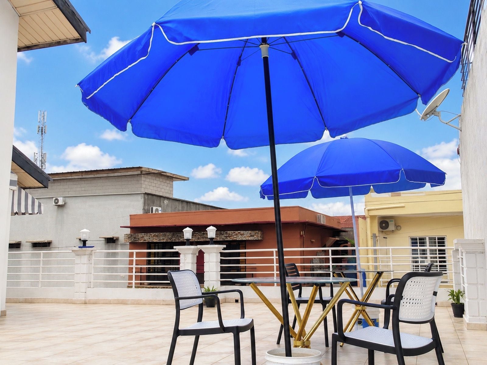 An outdoor seating area with blue umbrellas, tables, and chairs.