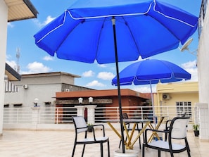 An outdoor seating area with blue umbrellas, tables, and chairs. - 4 Bedroom Villa Duplex Abidjan Cocody Riviera•Secured•2 Grandes terraces•WIFI•AC (Abidjan)
