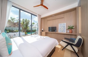 A hotel room with a large bed, a desk, a television, and a view of a pool and outdoor area. - Kata beach 4bedroom luxury pool villa (Karon)