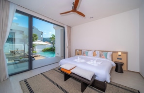 A hotel room with a bed, a bedside table, a ceiling fan, and a view of an outdoor pool and patio.