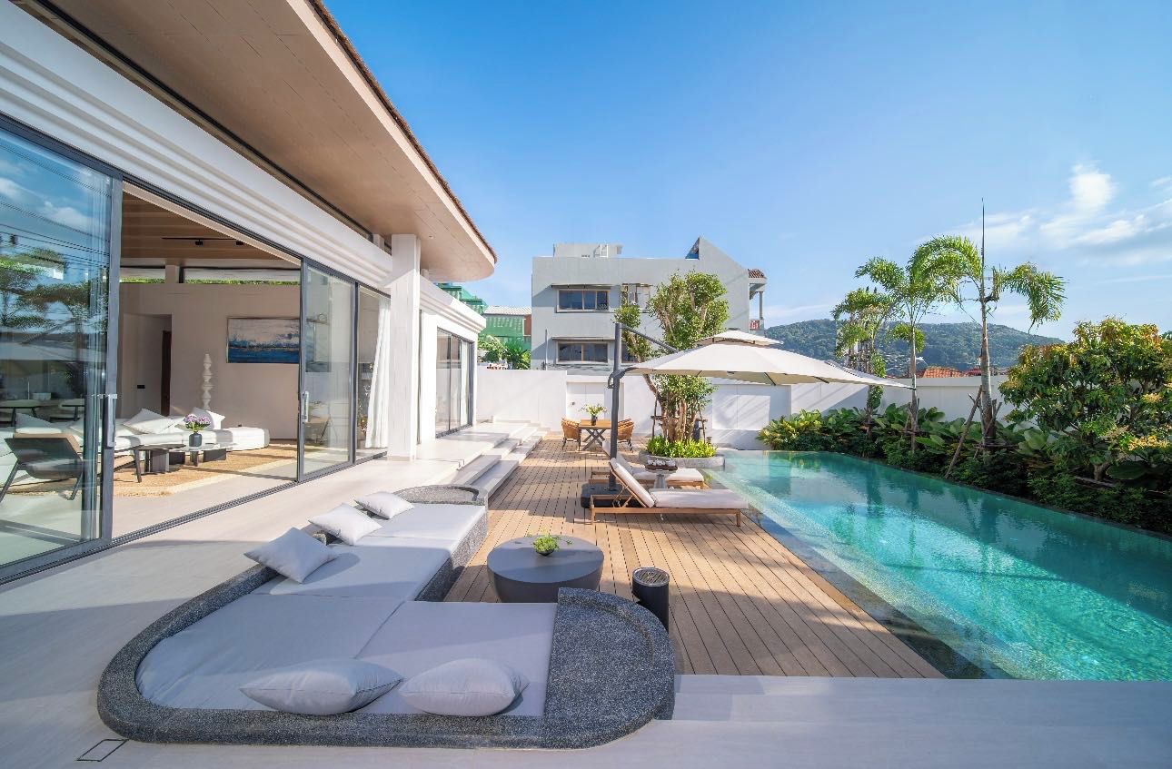 A modern outdoor pool area with lounge seating and a glass-enclosed patio.