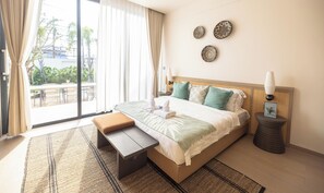 Habitación de hotel con cama, un banco, una mesita de noche, lámpara y vistas al exterior.