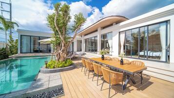 Una casa moderna con piscina, zona pranzo all'aperto e ampie finestre.