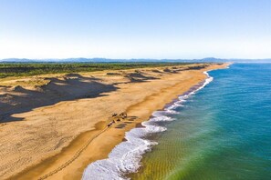 A coastal landscape with a sandy beach, a group of people on horseback, and a clear view of the ocean. - Villa Eau de Roche 5* (Moliets)