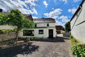 A residential property with a paved driveway, a small garden, and a two-story house with a dark roof. - Holiday home in Welling with Wi-Fi (Welling)