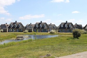 A row of traditional houses with a pond in the foreground. - Holiday apartment with 2 bedrooms (Julianadorp)