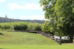 Een park met een gazon, bomen en een kasteel in de verte.