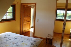 A bedroom with a bed, a wooden door, and a small table. - Holiday apartment with 1 bedroom (Rüdesheim)