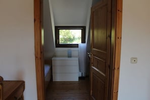 A narrow hallway leading to a room with a window, a wooden door, and a white bench. - Holiday apartment with 1 bedroom (Rüdesheim)