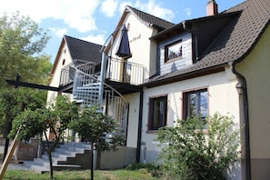 A two-story house with a spiral staircase leading to a balcony, surrounded by greenery. - Holiday apartment with 1 bedroom (Rüdesheim)