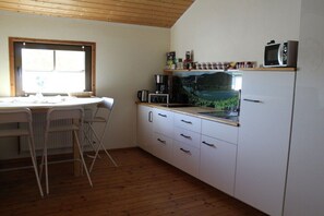 A compact kitchen with a dining table, chairs, a coffee maker, and a microwave. - Holiday apartment with 1 bedroom (Rüdesheim)