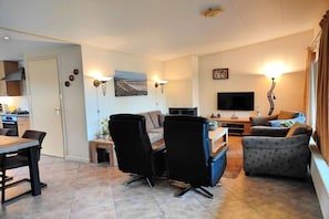 Ein Wohnzimmer mit einer Couch, Sesseln, einem Fernseher und einem Kamin.