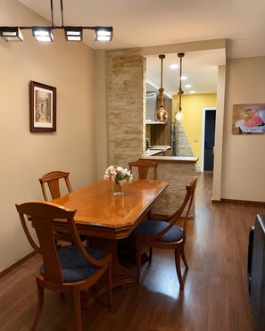 A dining area with a wooden table and chairs, a vase with flowers, and a stone wall. - Holiday Home 'Almerimar Golf Spacious Duplex Near' with Shared Pool, Wi-Fi and Air Conditioning (El Ejido)
