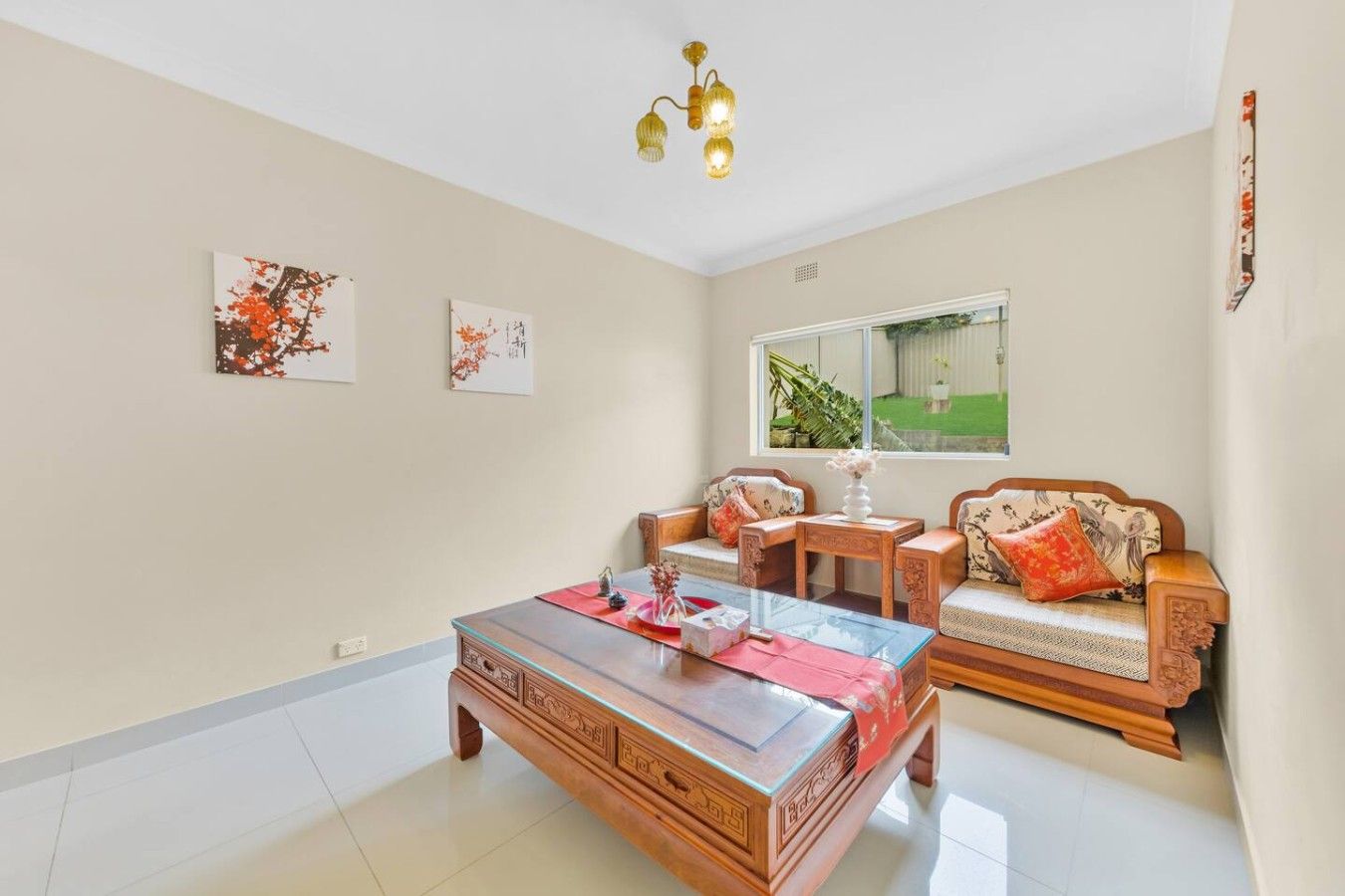 Un salon avec un canapé, une table basse et une fenêtre donnant sur un paysage verdoyant.