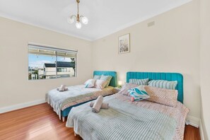 A bedroom with two beds, a window, and a ceiling light.