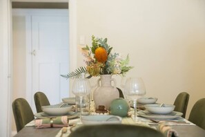 A dining table set with plates, bowls, and a vase of flowers.